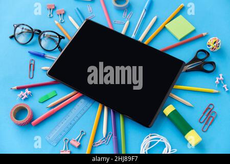 Tablet-pc und Schulbedarf auf blauem Hintergrund Stockfoto