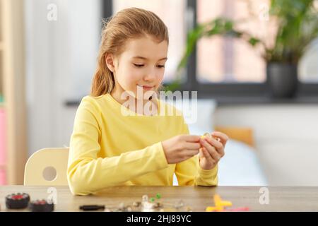 Glückliches Mädchen, das zu Hause mit einem Roboterbausatz spielt Stockfoto