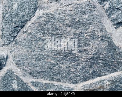 Nahaufnahme der Wand aus grauen, unregelmäßigen Granitsteinen Stockfoto