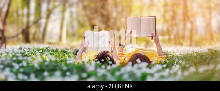 Mutter und ihr Sohn liegen auf dem schönen Frühlingsfeld im sonnigen Park. Stockfoto