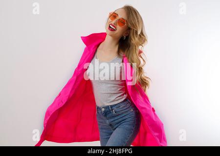 Close up glückliches Mädchen in roten Sonnenbrillen und rosa Mantel isoliert auf weißem Hintergrund. Aufgeregt, Schock und überrascht junge Frau, trendy Outfit. Mode und