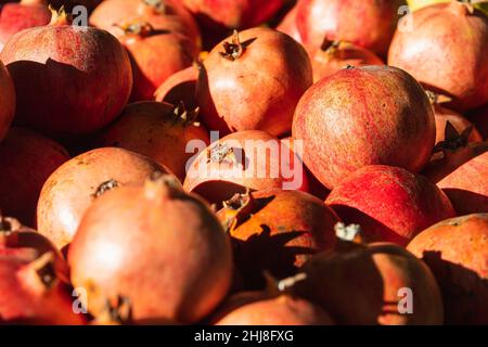 Nahaufnahme von hellen Früchten für Hintergrund, Textur. Rote reife Granatäpfel auf dem Display. Stockfoto