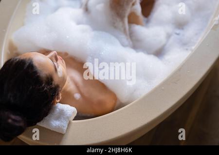 High-Angle-Ansicht der Biracial junge Frau in seifigen Badewanne im Spa entspannen. Spa, Körperpflege, Sinnlichkeit, Lifestyle, Vitiligo und Wellness. Stockfoto