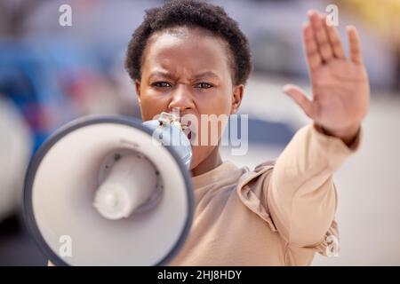 Kämpfe für das, woran du glaubst. Aufnahme einer jungen Frau mit erhobener Hand, die bei einem Protest durch ein Megaphon sprach. Stockfoto