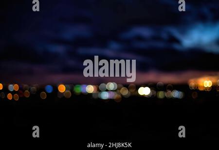Bokeh der Stadt Nacht Szene. Weichzeichnungseffekt durch Stadtlichter im Hintergrund. Defokussierte Lichter der Stadt bei Nacht mit Kopierplatz. Stockfoto