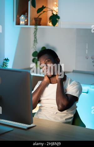 Erschöpfter müder Mann leidet Nackenschmerzen sitzen am Schreibtisch Arbeit am Computer zu Hause Gefühl Erschöpfung Stockfoto