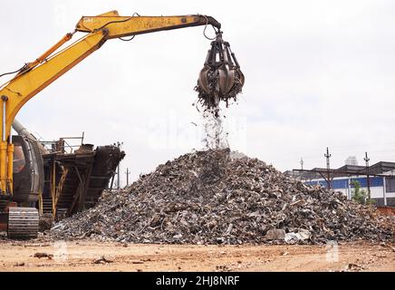 Industrielle Neuverwendung. Ausgeschnittene Aufnahme eines Baggers, der durch einen Haufen von Metallschrott sortiert. Stockfoto