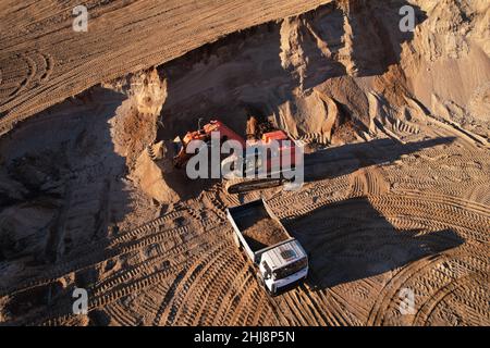 Der Bagger lädt den Sand in einen Muldenkipper im Tagebau. Entwicklung des Sandes im Tagebaus. Schwere Maschinen auf Erdarbeiten im Steinbruch. Miningtruck Stockfoto