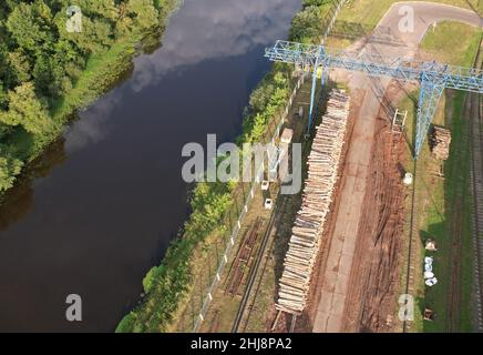 Holztruck, der einen Holzschnitt in der Holzbearbeitungsanlage ablädt. Transport von Rohholz von der Abfällstelle. Portalkran lädt Protokolle für Holzwerk. Ware Stockfoto