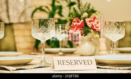 Reservierter Tisch in einem Restaurant mit Gläsern und einer roten Blume Stockfoto