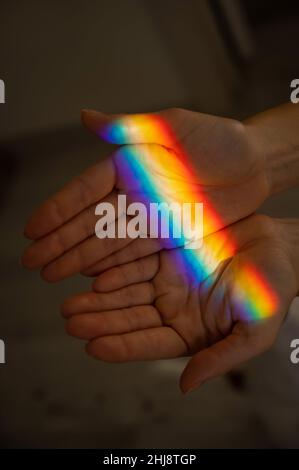 Regenbogenstrahl auf der Hand einer Frau. Stockfoto