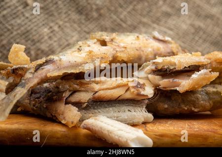 Gebratener Fisch und Pommes auf einem Schneidebrett auf einem Holztisch Stockfoto