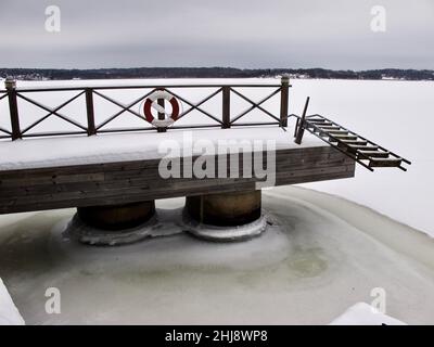 Brücke mit Leiter in der wolkigen Winterlandschaft mit gefrorenem Meer. Stockfoto