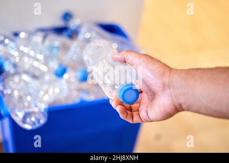 Recycling ist ein Lebensstil. Ein kurzer Schuss eines Mannes, der zu Hause eine Flasche in den Papierkorb legt. Stockfoto