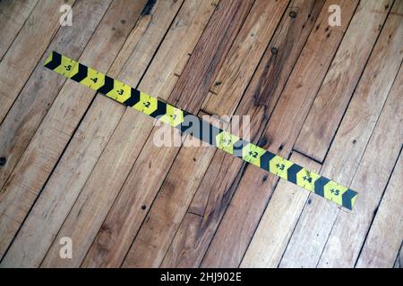 Die schwarz-gelben Messpfeile kleben auf den Holzboden in einem Spielzimmer Stockfoto