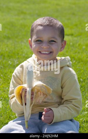 Kleiner Junge, der Banane isst Stockfoto