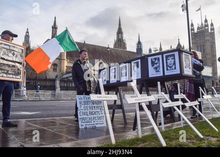 London, Großbritannien. 27th Januar 2022. Ein Demonstranten hält eine irische Flagge neben einem Sarg und kreuzt mit den Namen der Opfer des Blutigen Sonntags während der Gedenkfeier und Kundgebung.verschiedene Redner schlossen sich den Demonstranten auf dem Parliament Square vor dem 50th. Jahrestag des Blutigen Sonntags zu einer Gedenkfeier an, Und aus Protest gegen eine Amnestie für ehemalige britische Soldaten, die an den Morden von 1972 in Derry, Nordirland, beteiligt waren. (Foto: Vuk Valcic/SOPA Images/Sipa USA) Quelle: SIPA USA/Alamy Live News Stockfoto