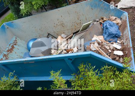 Ein großer blauer Müllcontainer mit sperrigen Abfällen Stockfoto