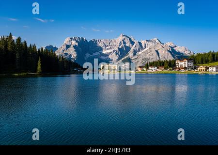 See und Stadt Misurina, Lago di Misurina, mit dem Berg Punta Sorapiss, der sich im Wasser spiegelt, L’istituto Pio XII am Ende des Sees. Stockfoto