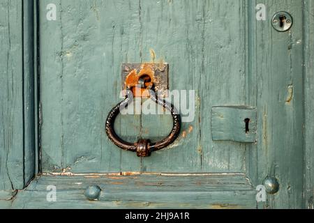 Robuster, gut abgenutzter Metallgriff an der alten, aus Holz lackierten Tür mit Schlüsselloch an der Seite Stockfoto