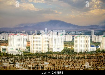 Stadtbild, Skyline mit marmorverkleideten hohen Gebäuden und neue Parks in Aschgabat, der Hauptstadt Turkmenistans in Zentralasien. Goldfarbenes Abendlicht. Stockfoto