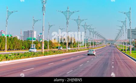 Stadtbild des Stadtzentrums von Ashgabat mit breiter Autobahn und leichtem Verkehr. Hohe Gebäude aus weißem Marmor an den Seiten. Aschgabat ist die Hauptstadt der Turkmenen Stockfoto