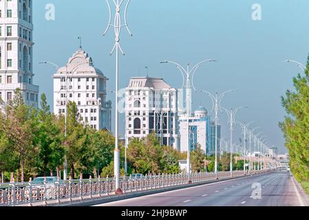 Stadtbild des Stadtzentrums von Ashgabat mit breiter Autobahn und leichtem Verkehr. Hohe Gebäude aus weißem Marmor an den Seiten. Aschgabat ist die Hauptstadt der Turkmenen Stockfoto