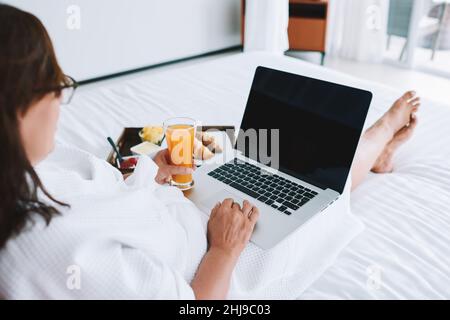 Frau, die am Laptop arbeitet und Saft trinkt Stockfoto