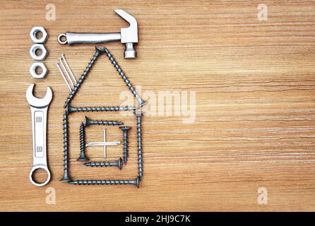 Haus Symbol aus Schrauben, Hammer, Schraubenschlüssel, Muttern und Nägel auf einem hölzernen Hintergrund, kopieren Raum. Stockfoto