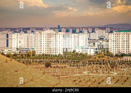 Stadtbild, Skyline mit marmorverkleideten hohen Gebäuden und neue Parks in Aschgabat, der Hauptstadt Turkmenistans in Zentralasien. Goldfarbenes Abendlicht. Stockfoto