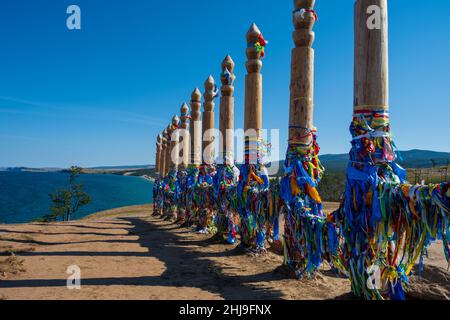 Bunte Bänder auf den Holzsäulen in der heiligen burjat Platz auf Kap Burkhan in Khuzhir Dorf in Olchon Insel, Baikalsee, Russland Stockfoto