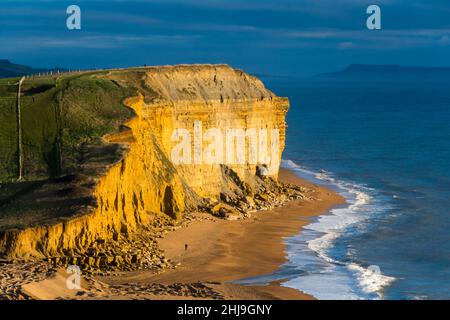 Burton Bradstock, Dorset, Großbritannien. 27th. Januar 2022. Wetter in Großbritannien. Am späten Nachmittag erhellt die Sonne die goldenen Sandsteinklippen und den Strand von Burton Bradstock an der Dorset Jurassic Coast, während die Wolken am Tag von überdurchschnittlichen Temperaturen kurz vor Sonnenuntergang klar werden. Bildnachweis: Graham Hunt/Alamy Live News Stockfoto