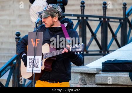 Ein Straßenmusiker. Ein süßer junger Mann spielt Gitarre und singt auf der Straße. Stockfoto