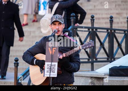 Ein Straßenmusiker. Ein süßer junger Mann spielt Gitarre und singt auf der Straße. Stockfoto