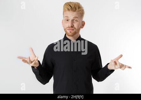 Verwirrt Kerl in schwarzem Hemd isoliert. Der junge Mann weiß nicht, was er wählen soll. Männer treffen ein Entscheidungskonzept. Speicherplatz kopieren. Kaukasischer rothaariger Mann mit st Stockfoto
