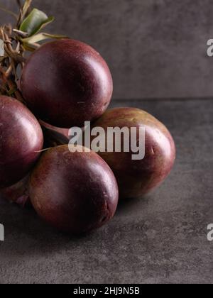 Foto zeigt mehrere lila tropische Früchte. Eine Frucht wird aufgeschnitten und das Innere ist sichtbar. Caimito Fruit stammt aus dem Dschungel der Dominikanischen Repu Stockfoto