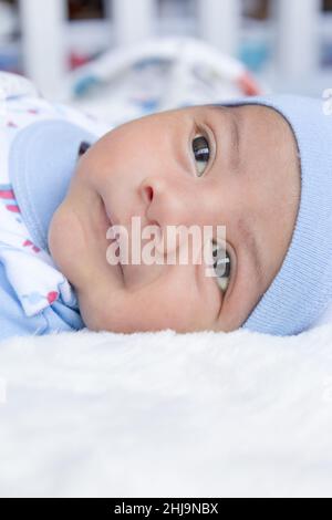 Lächelnder Junge, der herumliegt, auf seinem Bett liegt, einen neugeborenen Lebensstil, ein neues Leben und ein Familienmitglied zu Hause Stockfoto