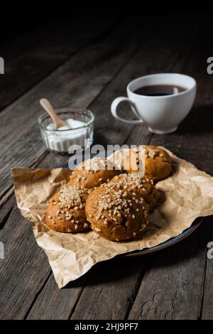 Ein Frühstücksteller mit gebackenen Walnussmuffins, dunklem Kaffee und einer Schüssel mit Zucker auf einer schwarzen Holzplatte. Stockfoto