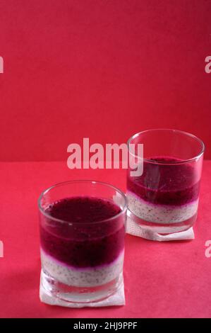 Foto zeigt veganes Dessert im Glas. Gesundes Essen hat zwei Schichten von Weiß mit Chia-Samen aus Joghurt und Top - rosa, aus Pitahaya-Saft hergestellt. Pi Stockfoto