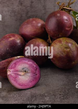 Foto zeigt mehrere lila tropische Früchte. Eine Frucht wird aufgeschnitten und das Innere ist sichtbar. Caimito Fruit stammt aus dem Dschungel der Dominikanischen Repu Stockfoto