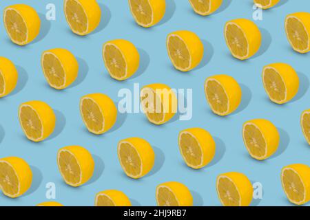 Trendiges Sommermuster mit gelber Zitronenscheibe auf hellblauem Hintergrund. Minimales Sommerkonzept. Stockfoto