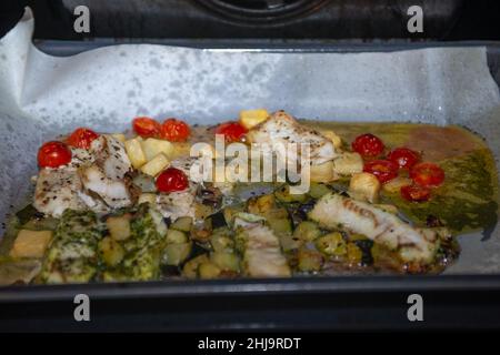 Kabeljaufilet mit Kartoffeln und Kirschtomaten, die im Ofen gebacken werden Stockfoto