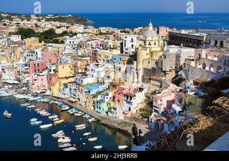 Panoramablick auf die schöne Procida in sonnigen Sommertag. Bunte Häuser, Fischerboote und Yachten in Marina Corricella, Procida, Italien, Neapel Stockfoto