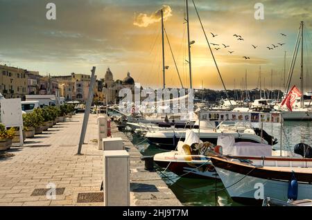 Ein wunderschöner Sonnenuntergang, der sich auf die bunten Häuser des Hafens von procida spiegelt Stockfoto