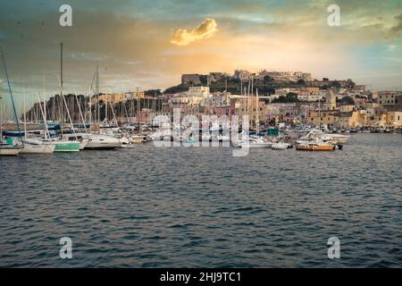 Ein wunderschöner Sonnenuntergang, der sich auf die bunten Häuser des Hafens von procida spiegelt Stockfoto