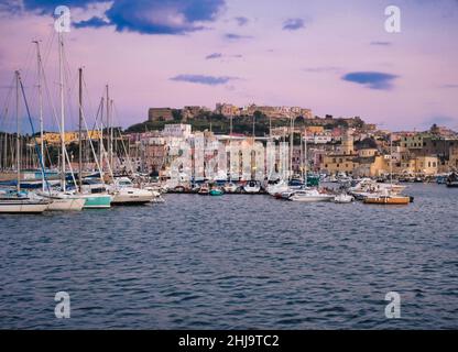 Ein wunderschöner Sonnenuntergang, der sich auf die bunten Häuser des Hafens von procida spiegelt Stockfoto