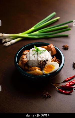 Asiatische Schüssel mit süßem Schweinefleisch, Ei, Reiskugel, grünen Zwiebeln, roten Chilischoten und Sternanis. Stockfoto