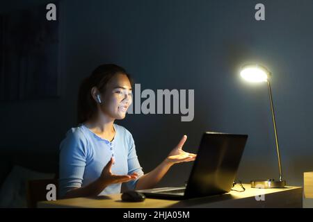Asiatische Frauen, die zu Hause arbeiten, sitzen nachts zu Hause mit Kollegen oder Managern per Videoanruf bei der Arbeit. Stockfoto