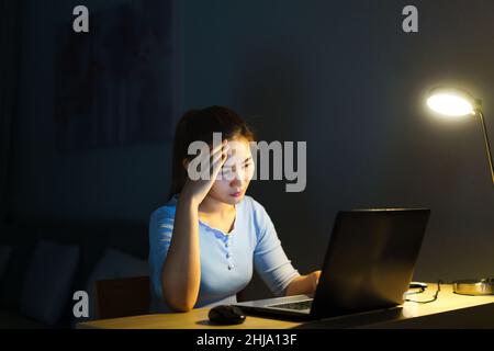 Asiatische Frau arbeiten spät in der Nacht stressig mit Projektforschungsproblemen auf einem Laptop-Computer oder Notebook zu Hause Büro Burnout-Syndrom Konzept. Stockfoto