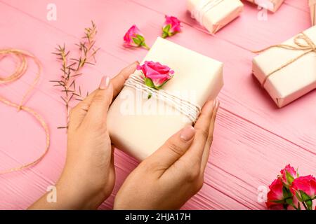 Frau mit schöner Geschenkbox auf rosa Holzhintergrund, Nahaufnahme Stockfoto